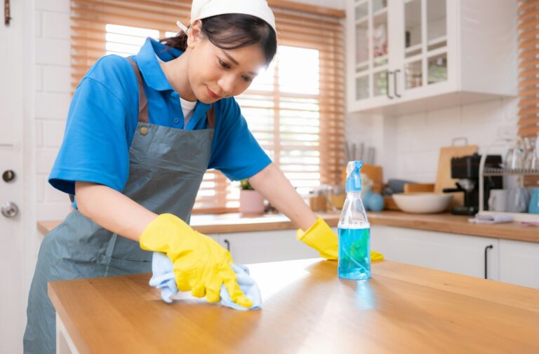 Young woman cleaning the table in the kitchen. Housekeeping and housekeeping concept.